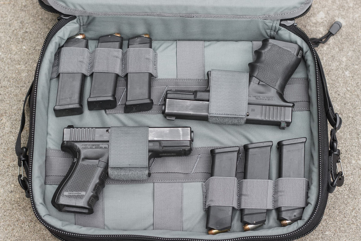 Gray tactical bag with firearms and magazines on a concrete floor