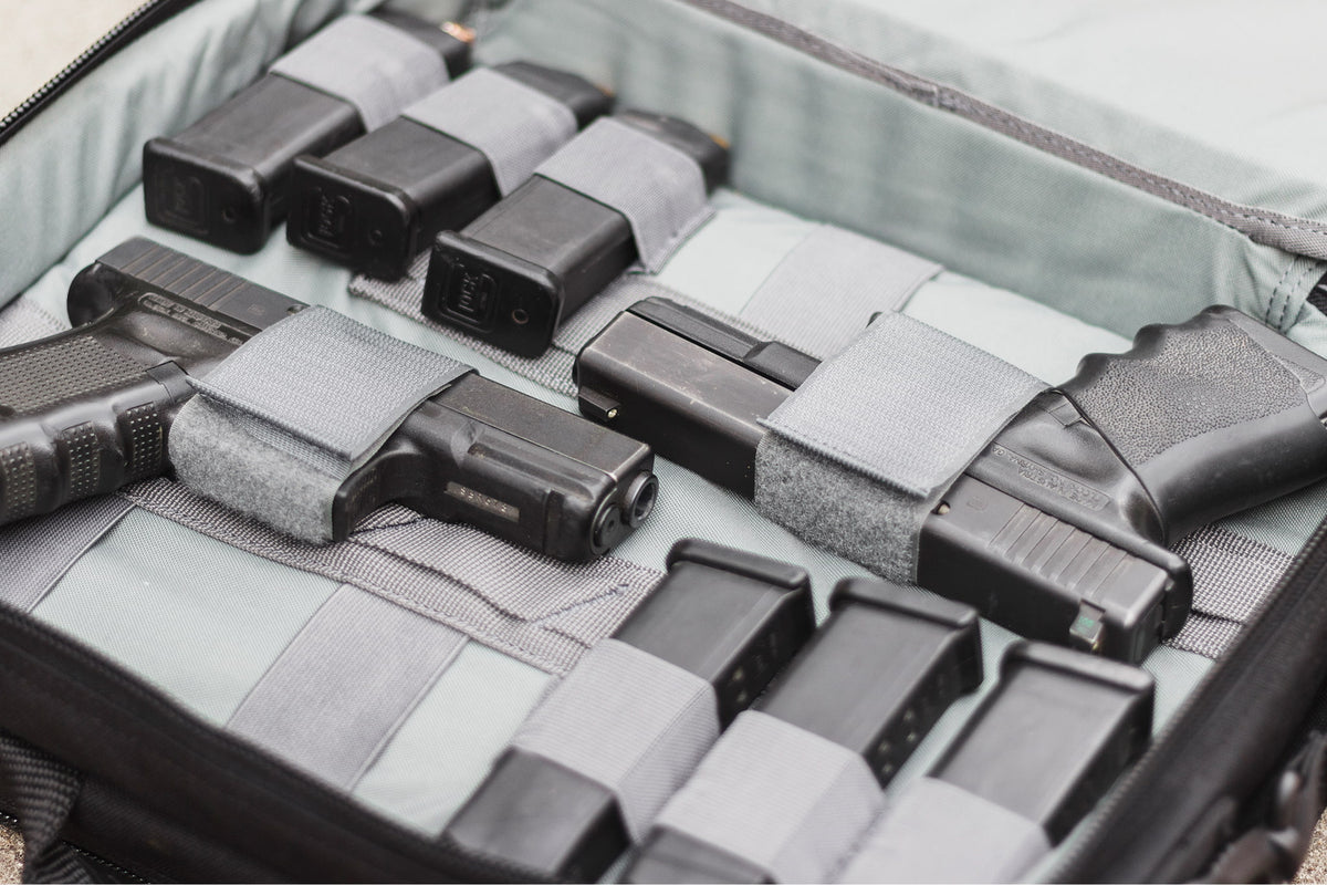 Collection of black firearms and magazines in a gray case