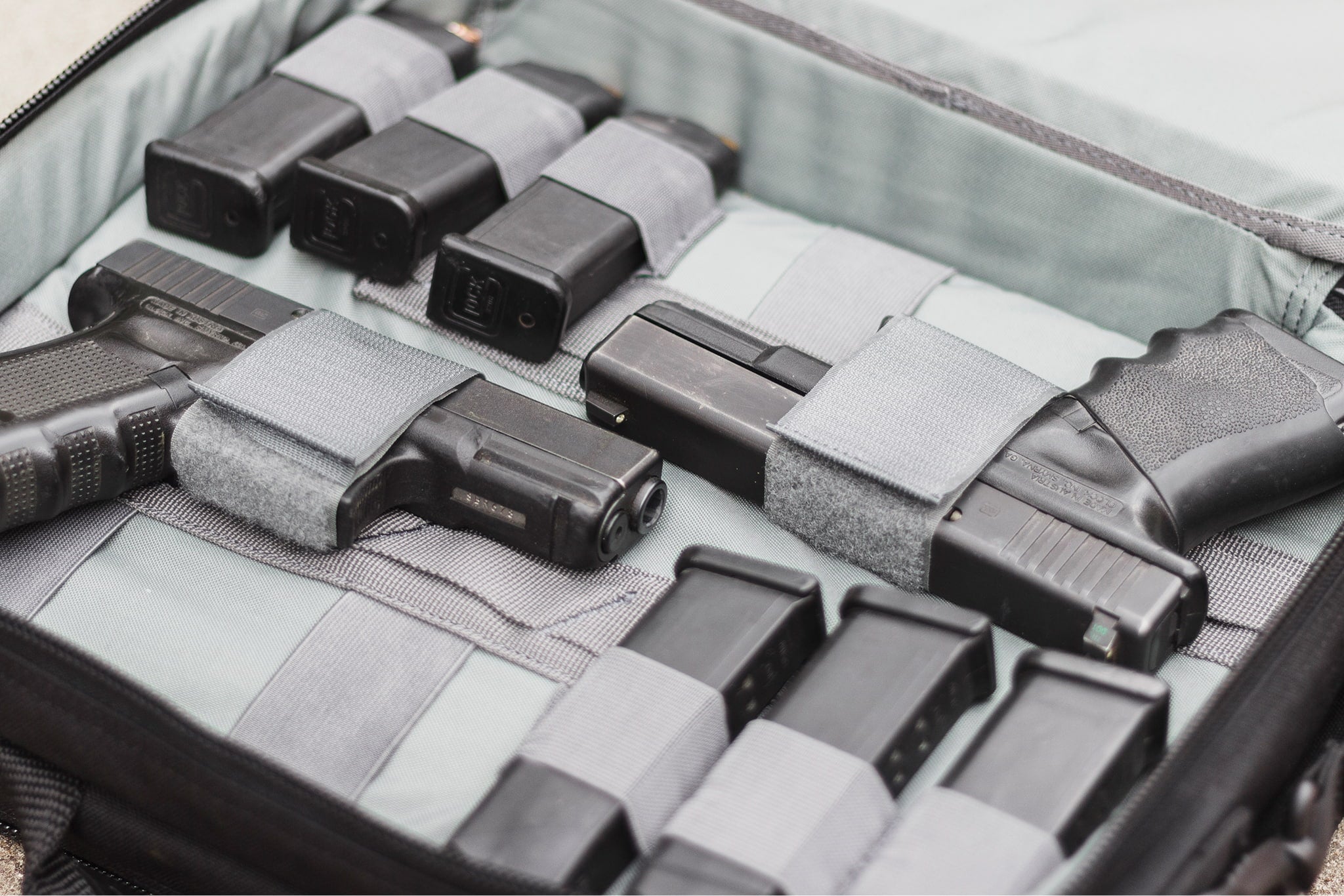 Collection of black firearms and magazines in a gray case