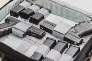 Collection of black firearms and magazines in a gray case