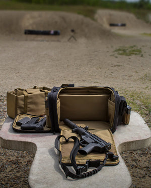 Coyote brown tactical range bag with a gun and magazines on a concrete surface at a shooting range.