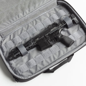 Black rifle inside a gray protective case on a white background