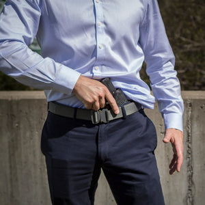 Person wearing a light blue shirt and dark pants with a tactical belt and gun holster.