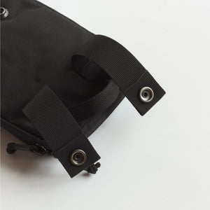 Close-up of a black tactical pouch with grommets on a white background
