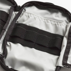 Close-up of a backpack interior with black straps and zippers.
