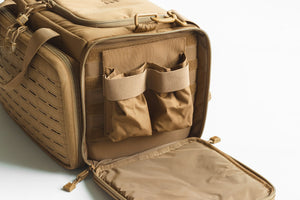 Open tan tactical bag with multiple compartments on a light gray background