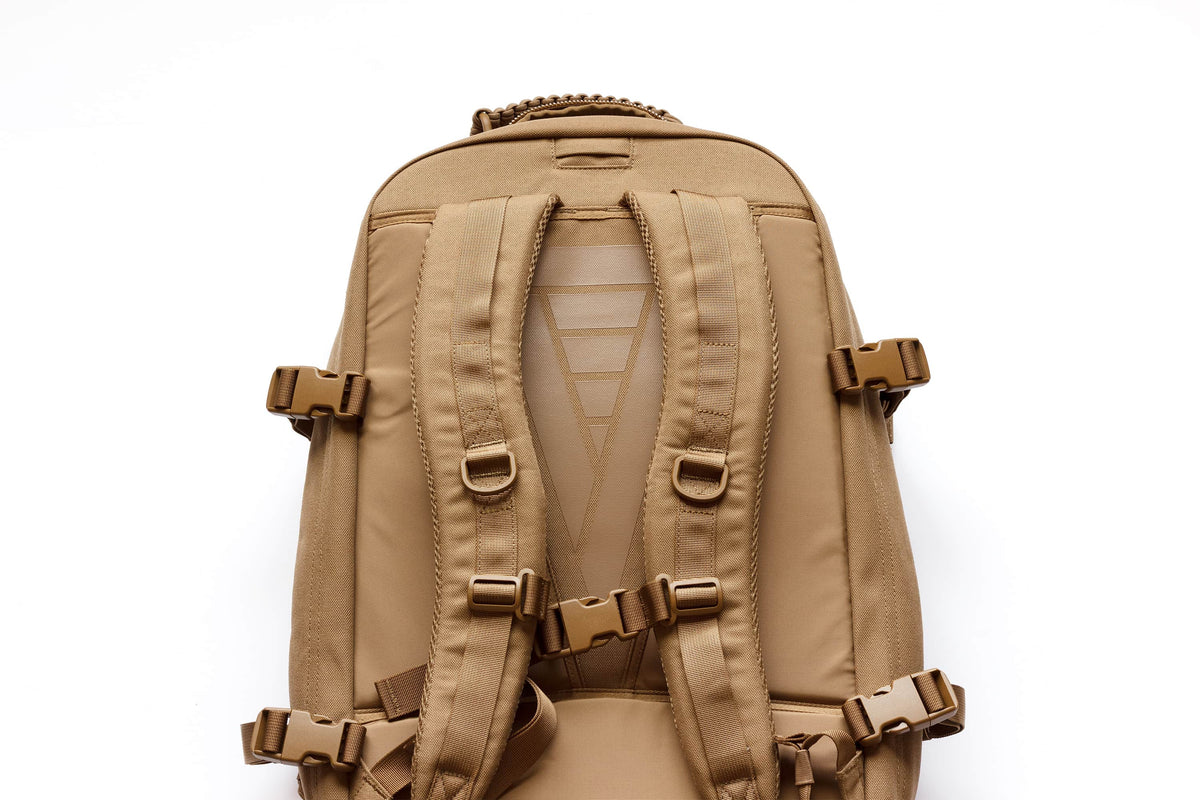 Close-up of the Strike backpack's padded shoulder straps, sternum strap, and D-ring attachment points in coyote tan