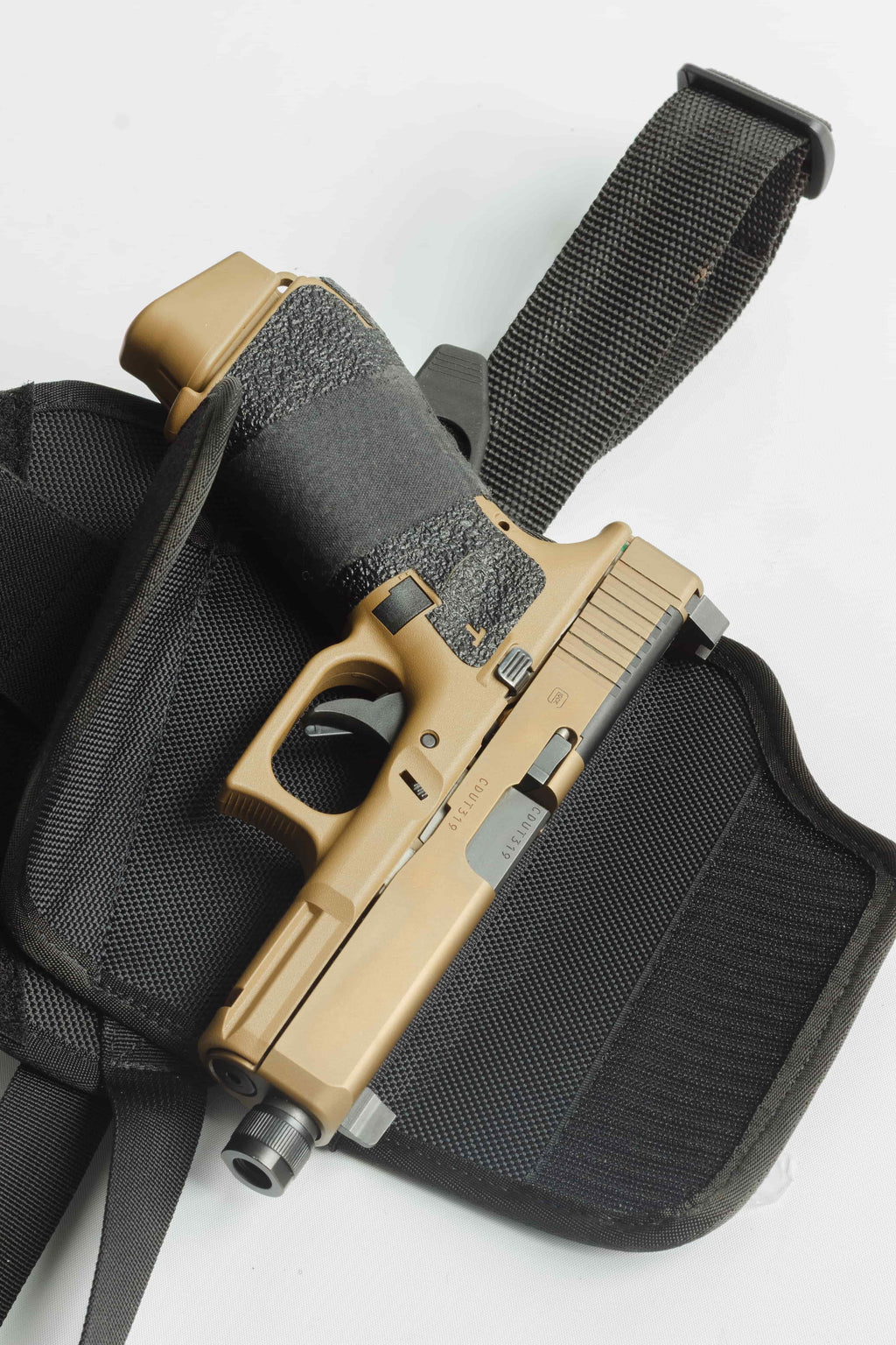 Tan handgun in a black holster on a white background
