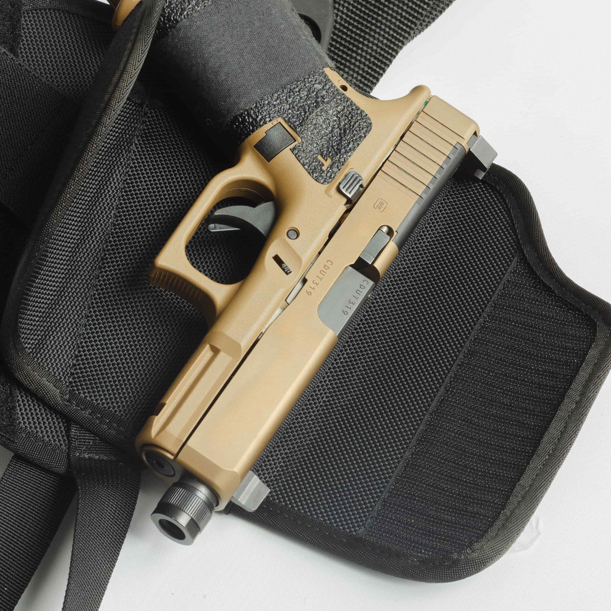 Tan handgun in a black holster on a white background