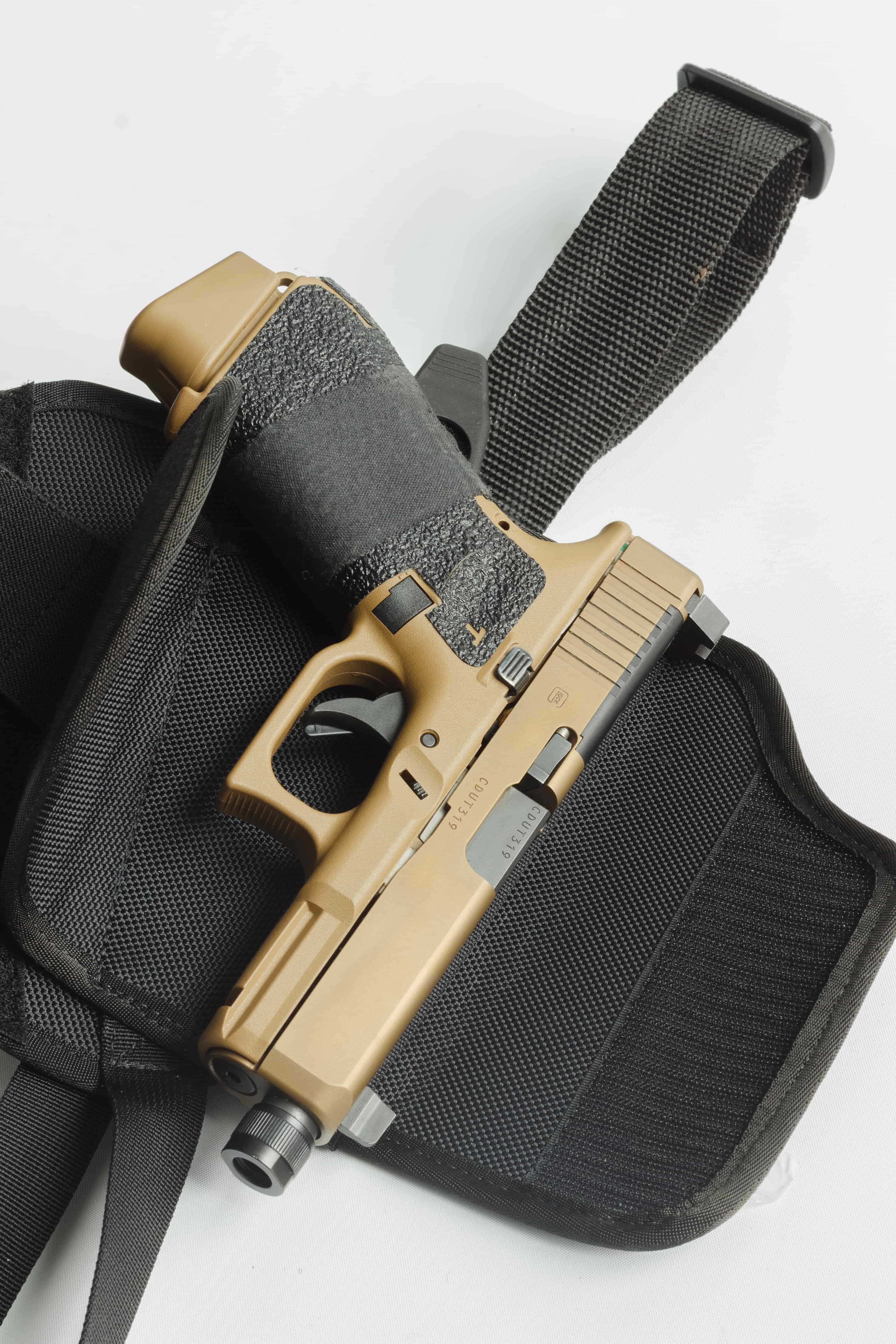 Tan handgun in a black holster on a white background