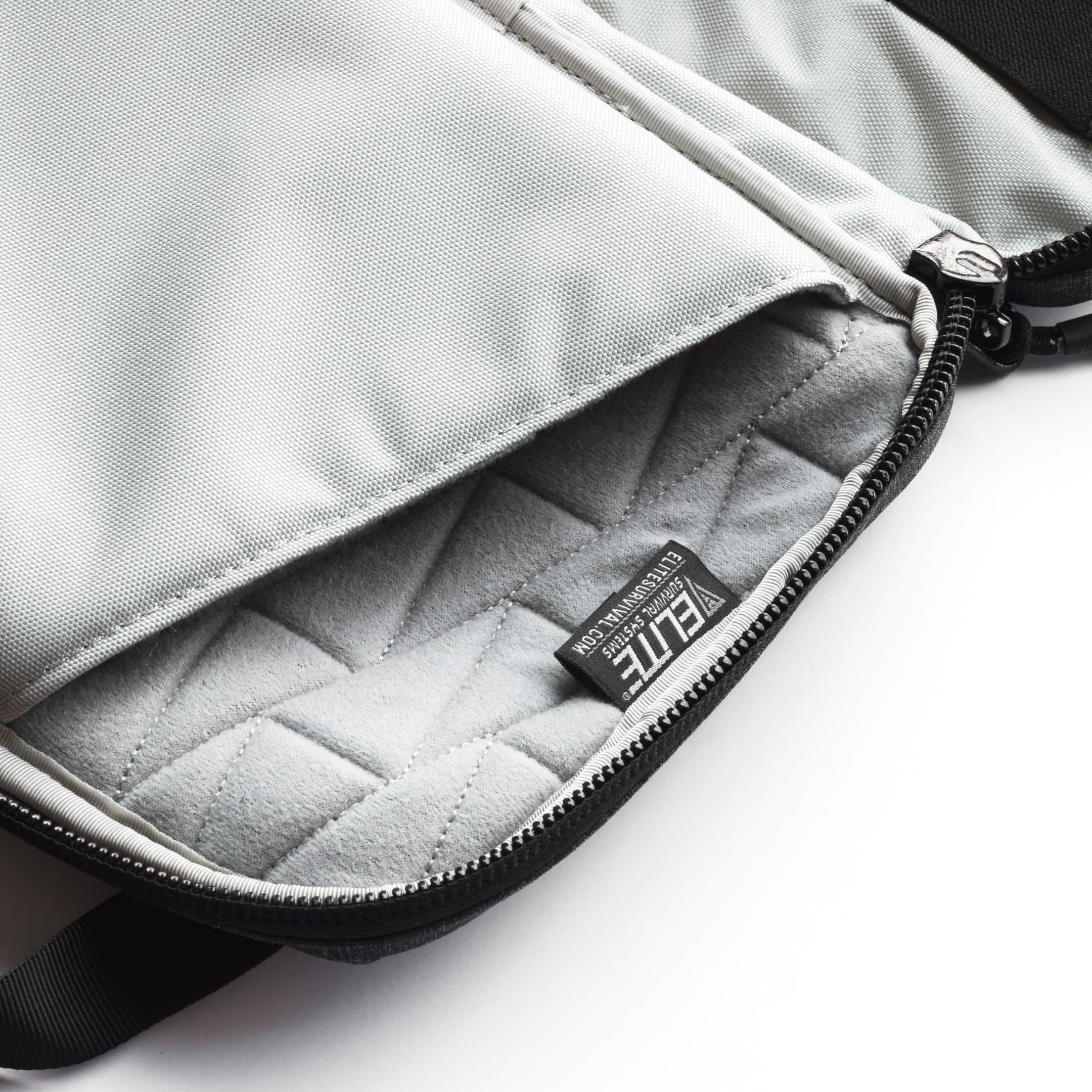 Close-up of a light gray fabric bag showing the interior lining, black zipper, and a small black brand tag reading ETE.