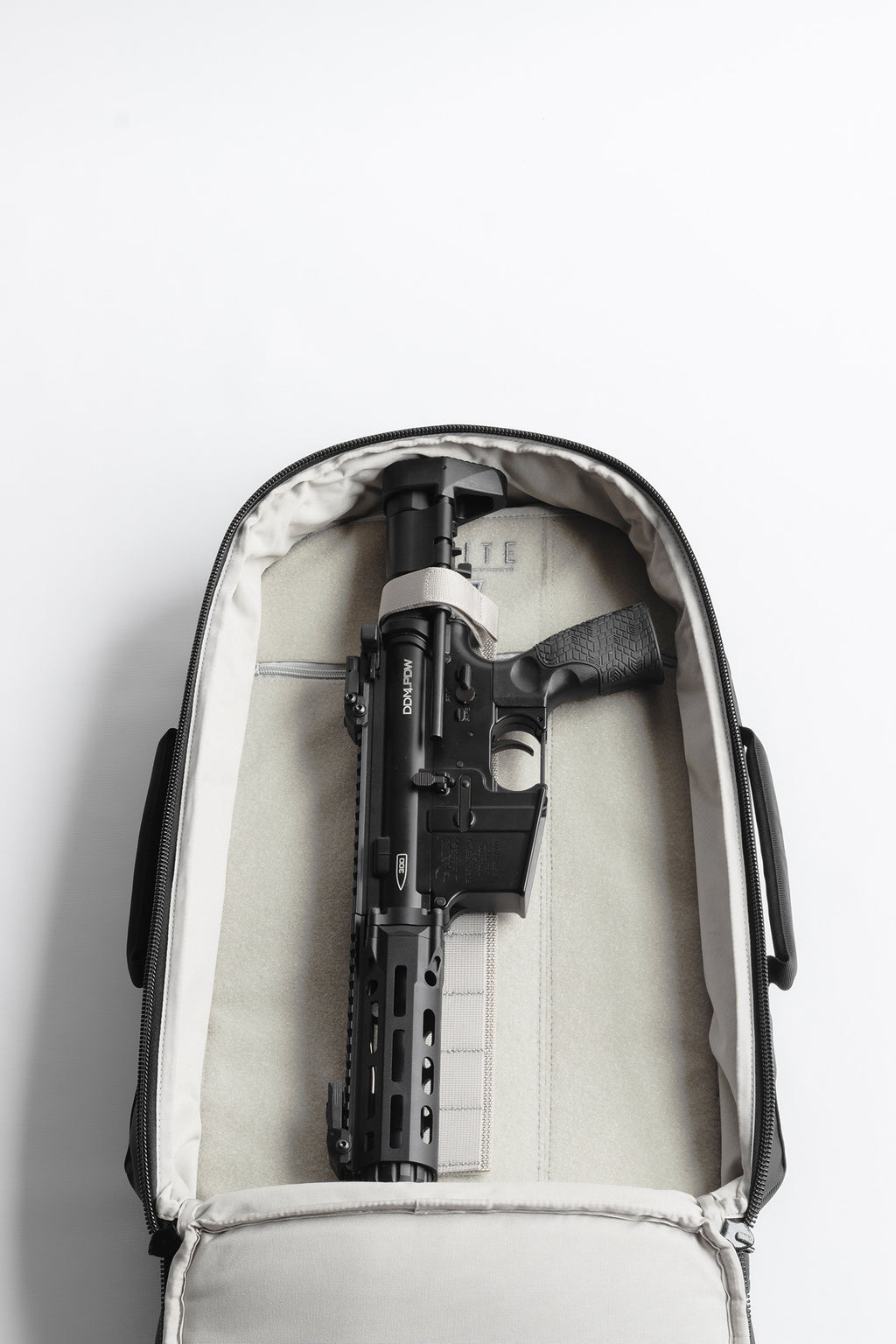 Black rifle inside a white suitcase on a light gray background