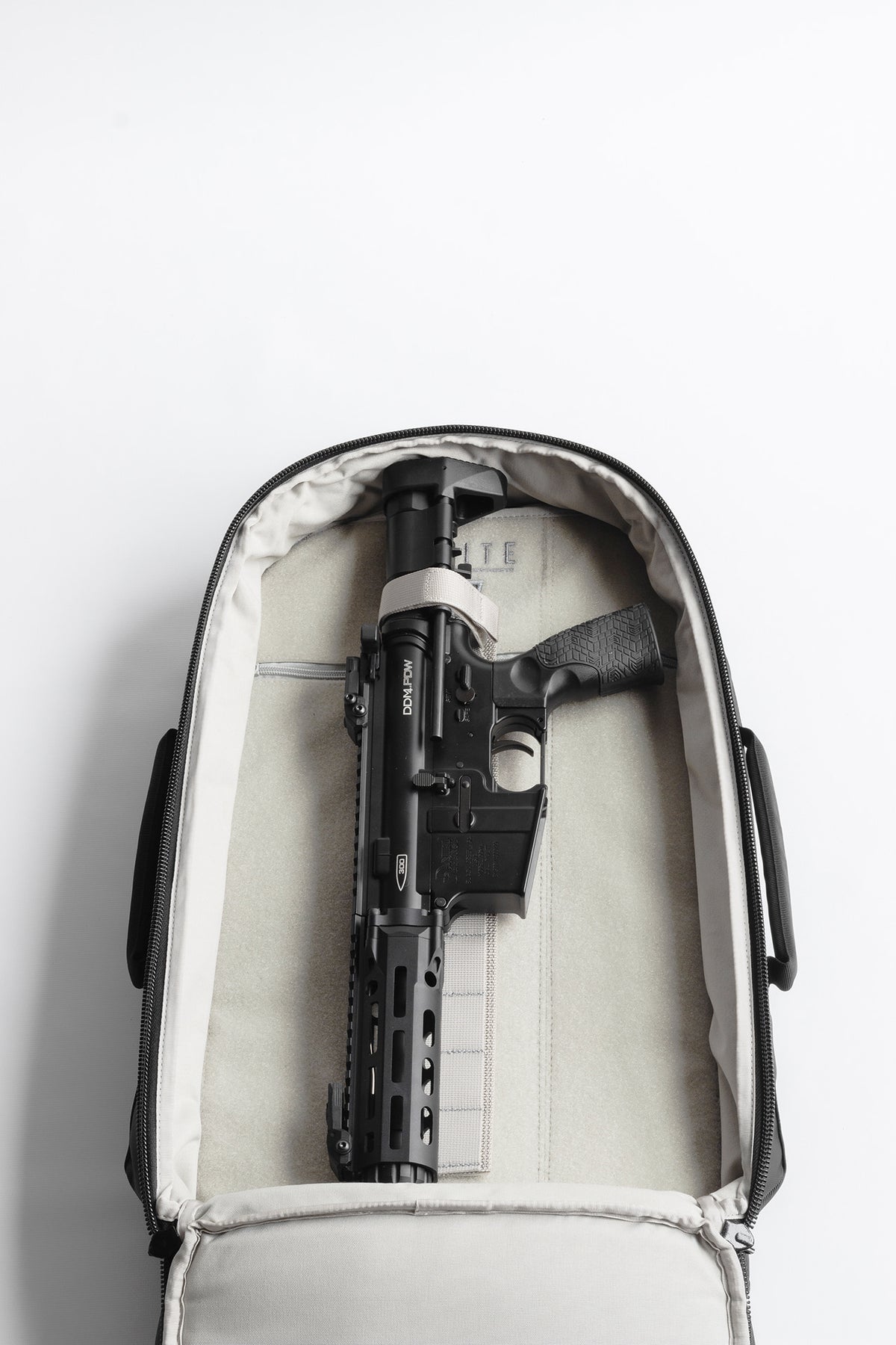 Black rifle inside a white suitcase on a light gray background