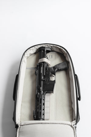 Black rifle inside a white suitcase on a light gray background