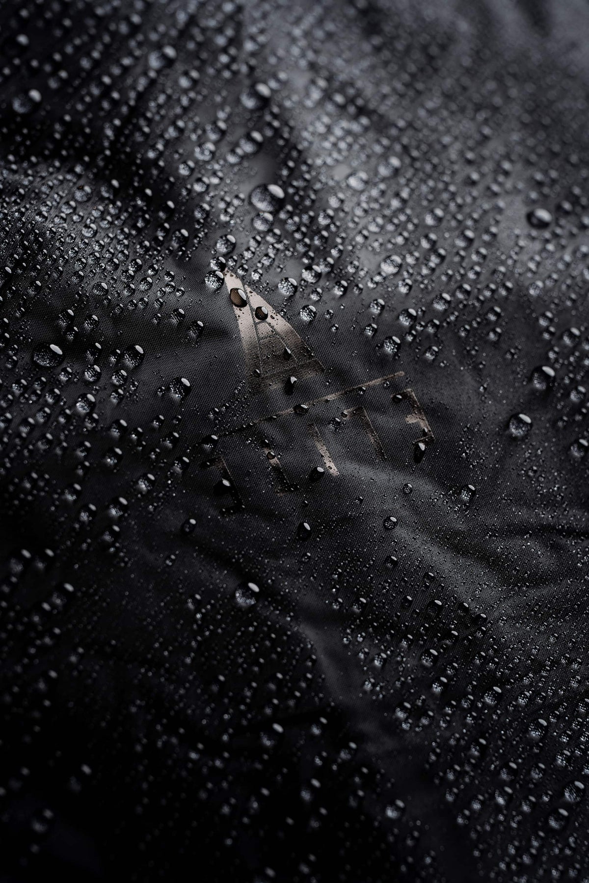 Close-up of water droplets beading on the black Mission Backpack 40L fabric