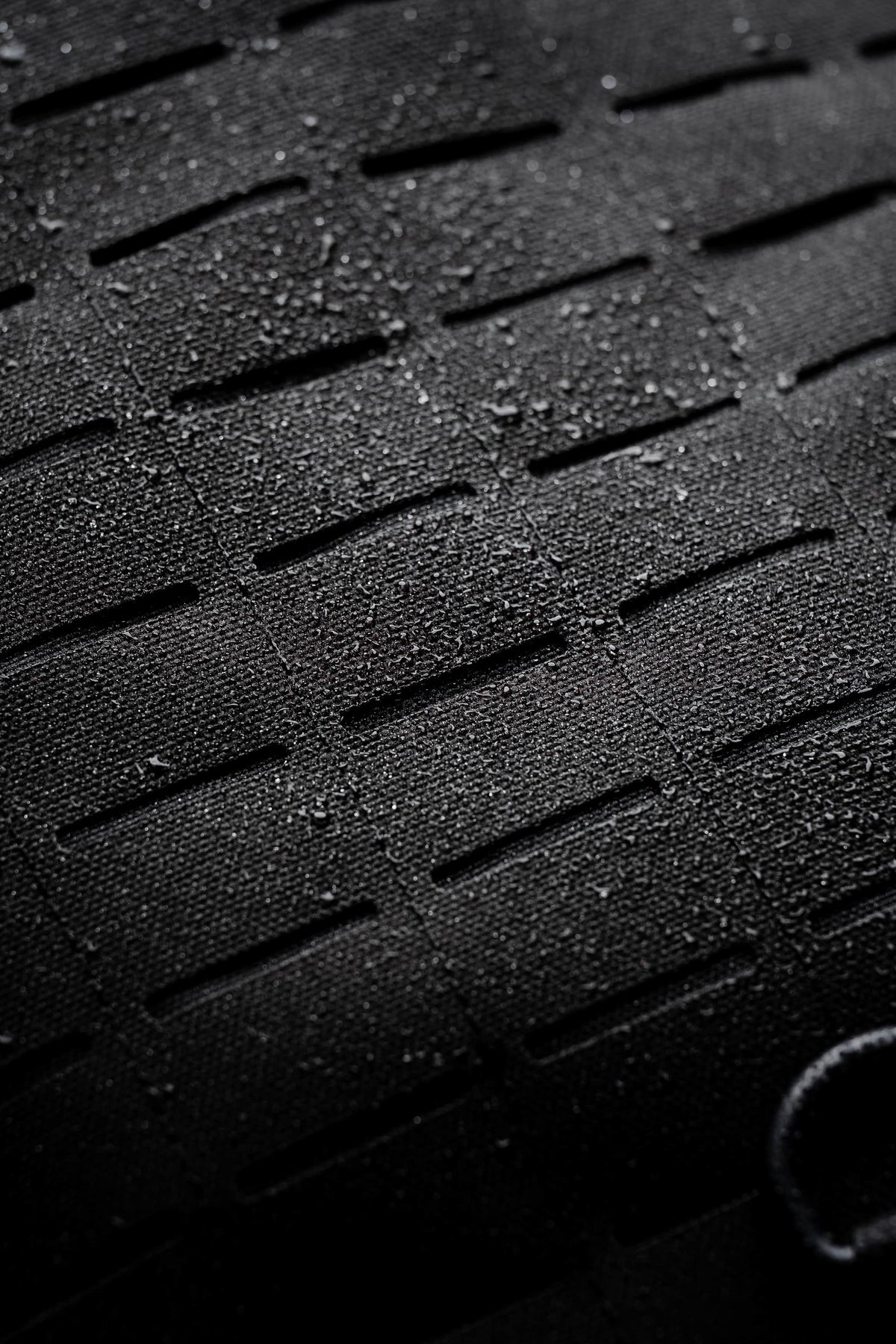 Close-up of water droplets on the laser-cut MOLLE panel of the Mission Backpack 40L