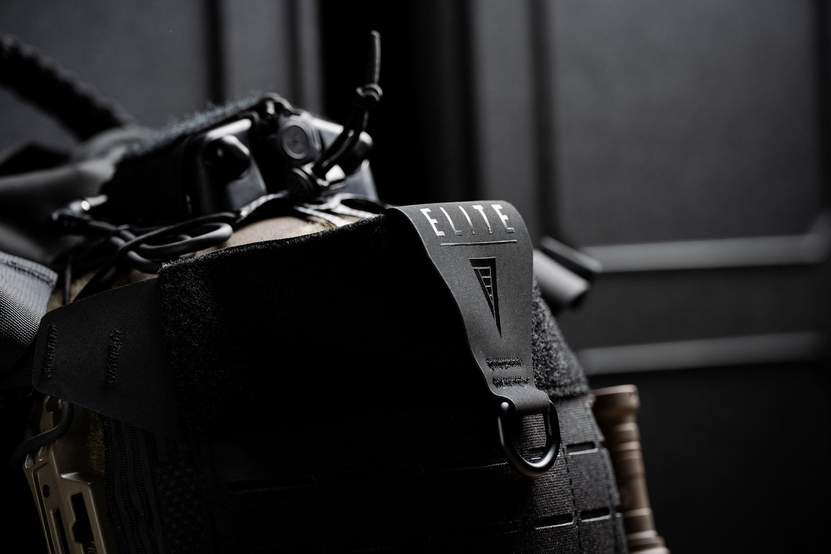 Black Mission Backpack 40L with the ELITE logo sitting in front of black hard rifle cases