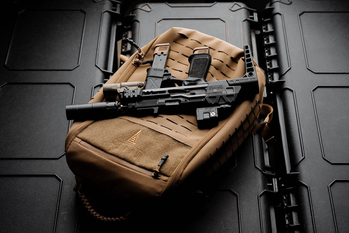 Compact pistol in a stock chassis lying on top of the coyote Apex backpack on a black gun case